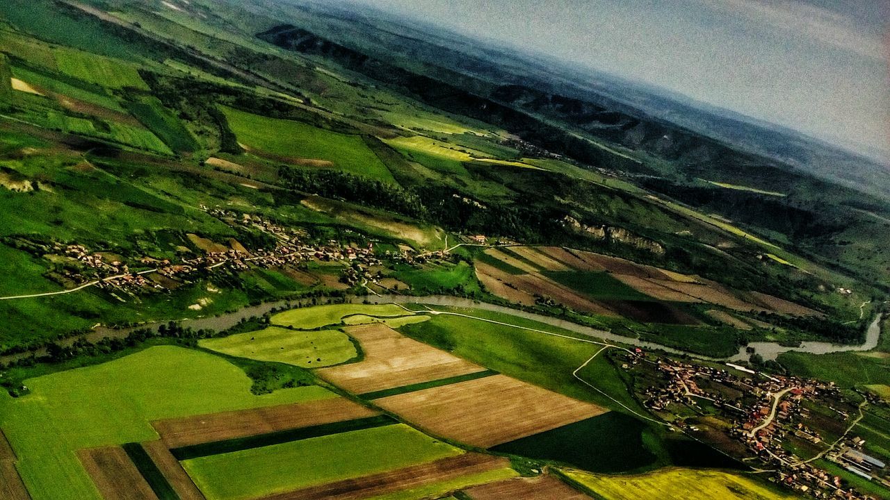 high angle view, landscape, green color, agriculture, rural scene, field, farm, built structure, building exterior, grass, architecture, nature, tranquility, tranquil scene, scenics, beauty in nature, tree, growth, house, aerial view