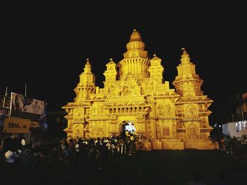 People at illuminated temple against sky at night