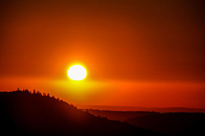 Scenic view of silhouette mountains against orange sky