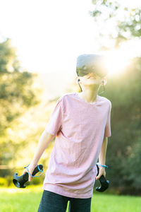 Tween having virtual experience with vr goggles outside in green field