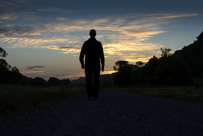 Rear view of silhouette man walking on landscape