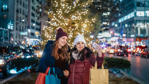 Happy friends on illuminated city street