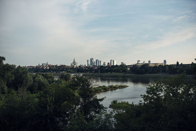 Scenic view of river by buildings against sky