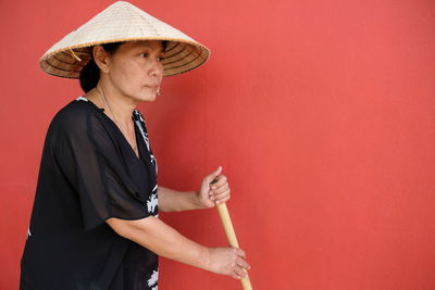 Midsection of woman holding red while standing against wall