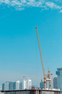 Crane by building against blue sky