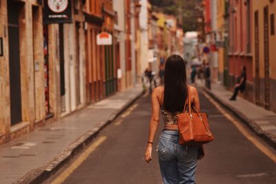 Rear view of woman walking on street in city