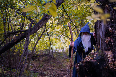 Man standing by tree in forest