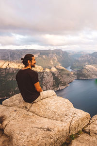 Man smiling sitting in rock at edge of cliff at preikestolen, norway