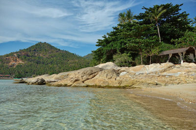 Scenic view of rocks by sea against sky