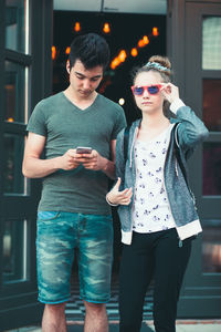 Smiling teenage friends using mobile phone in city