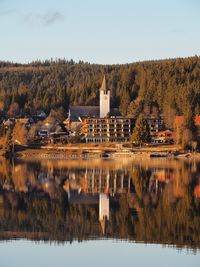 Reflection of building and trees in lake against sky