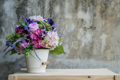 Close-up of flower pot on table against wall