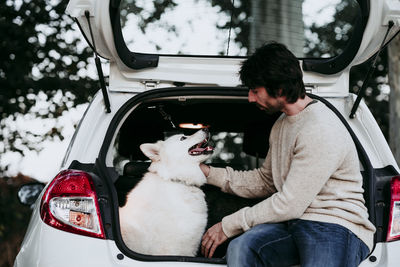 Man with dog sitting in car