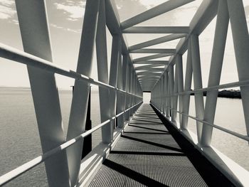 Metallic footbridge over sea during sunny day