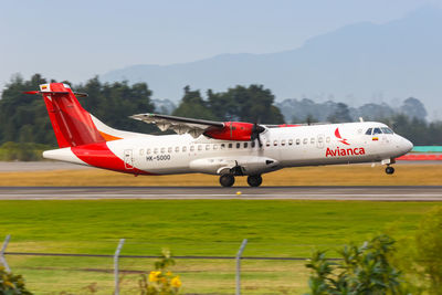 Airplane flying over airport runway against sky