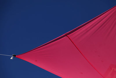 Low angle view of red umbrella against blue sky