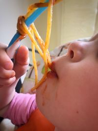 Cropped image of baby girl eating spaghetti