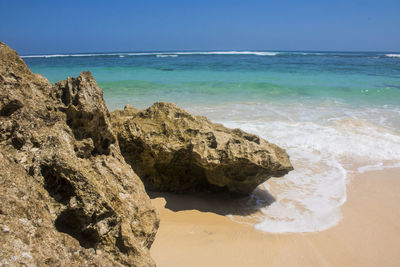 Scenic view of rocks on beach against sky