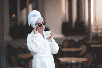 Portrait of smiling woman wearing sunglasses at cafe