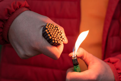 Close-up of hand holding lit candles