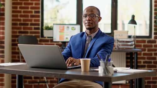Portrait of businessman with laptop at desk