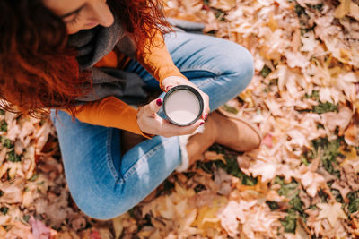 Midsection of woman holding autumn leaves on field