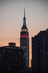 Illuminated empire state building against sky during sunset