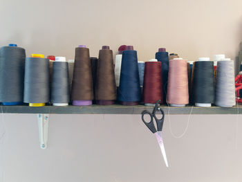 Spools of threads in various colors for sewing with hanging scissor.