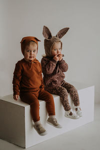 Toddler twins in funny hats with ears sitting and smiling