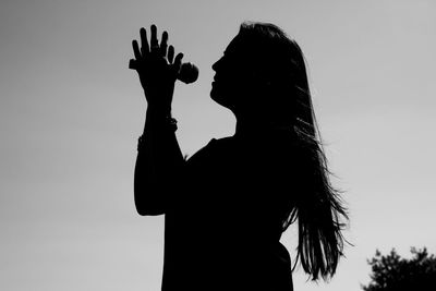 Silhouette woman singing on microphone against sky