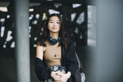 Portrait of teenage girl with sports ball in parking garage