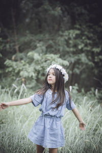 Cute girl wearing flowers standing on grassy field