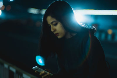 Young woman using phone at night