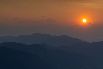 Scenic view of silhouette mountains against orange sky