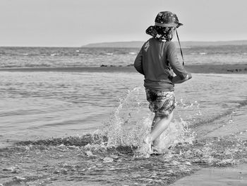 Rear view of boy running by the beach