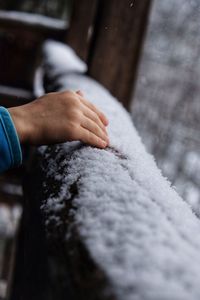 Cropped hand of woman touching snowy railing