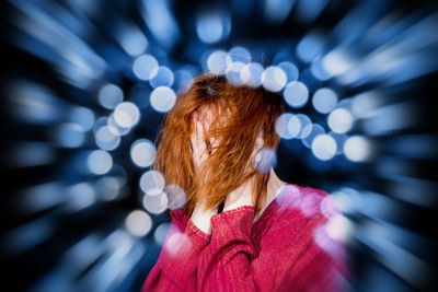 Woman with hands covering face amidst illuminated lens flare