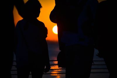 Silhouette people standing against sky during sunset