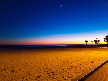 Scenic view of beach against clear sky at sunset