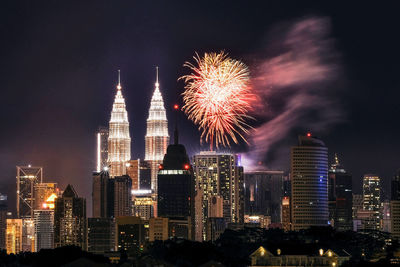 Firework display over illuminated buildings in city at night