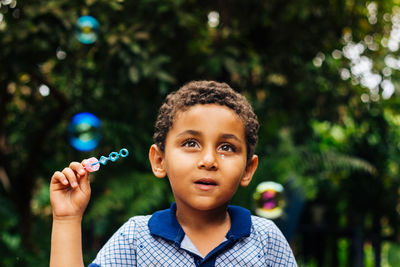 Boy blowing bubbles in park