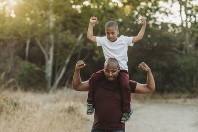 Close up portrait of school-aged son sitting on father's shoulders