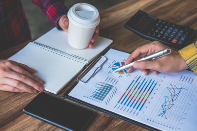 Cropped image of business colleagues analyzing paperwork on table