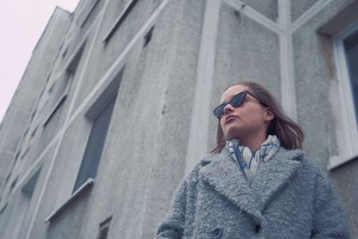 Low angle view of woman looking away against building in city