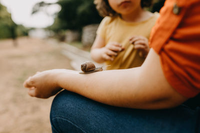 Midsection of woman holding snail on the arm