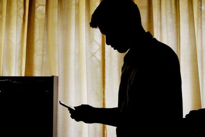 Side view of silhouette man against curtain