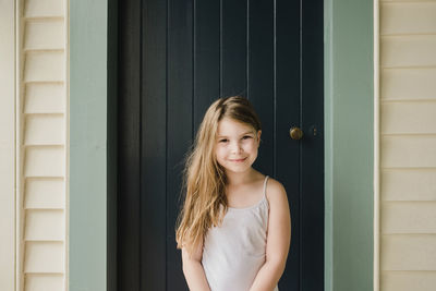 Portrait of a smiling young woman standing against wall