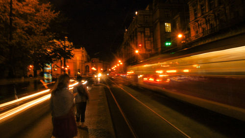 Blurred motion of train on illuminated railroad tracks in city at night