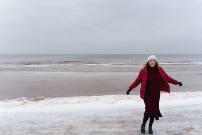 Smiling woman runs along the seashore in winter