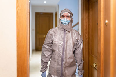 Portrait of doctor wearing protective suit while standing indoors